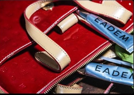 EADEM tubes spilling from a patent red bag — glossy red mood